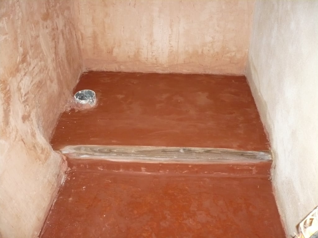 Pavimento a calce in bagno con scalino in legno antico. | Lime floor in the bathroom with antique wooden step.